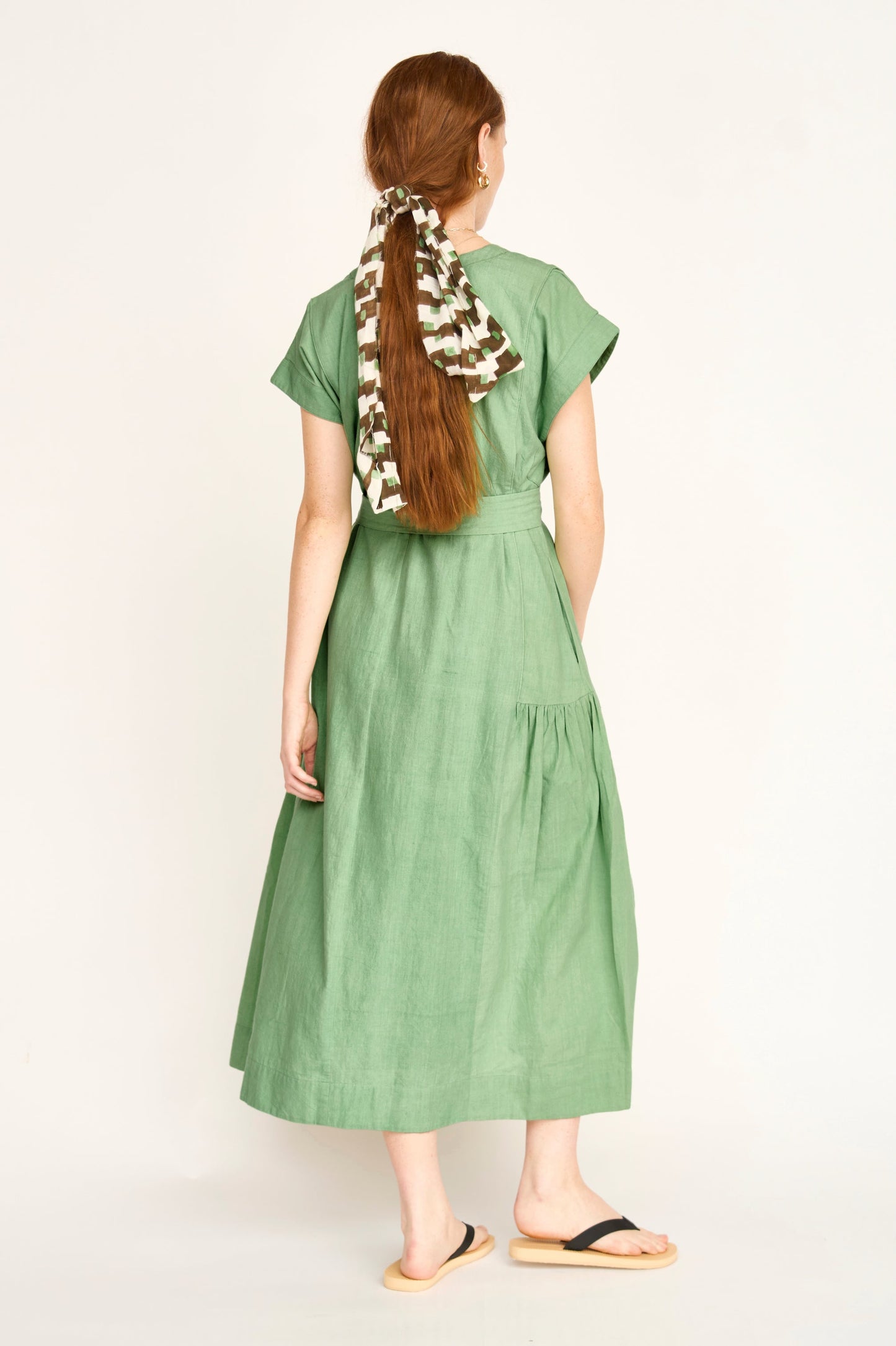 Green cotton midi dress on a hanger in store