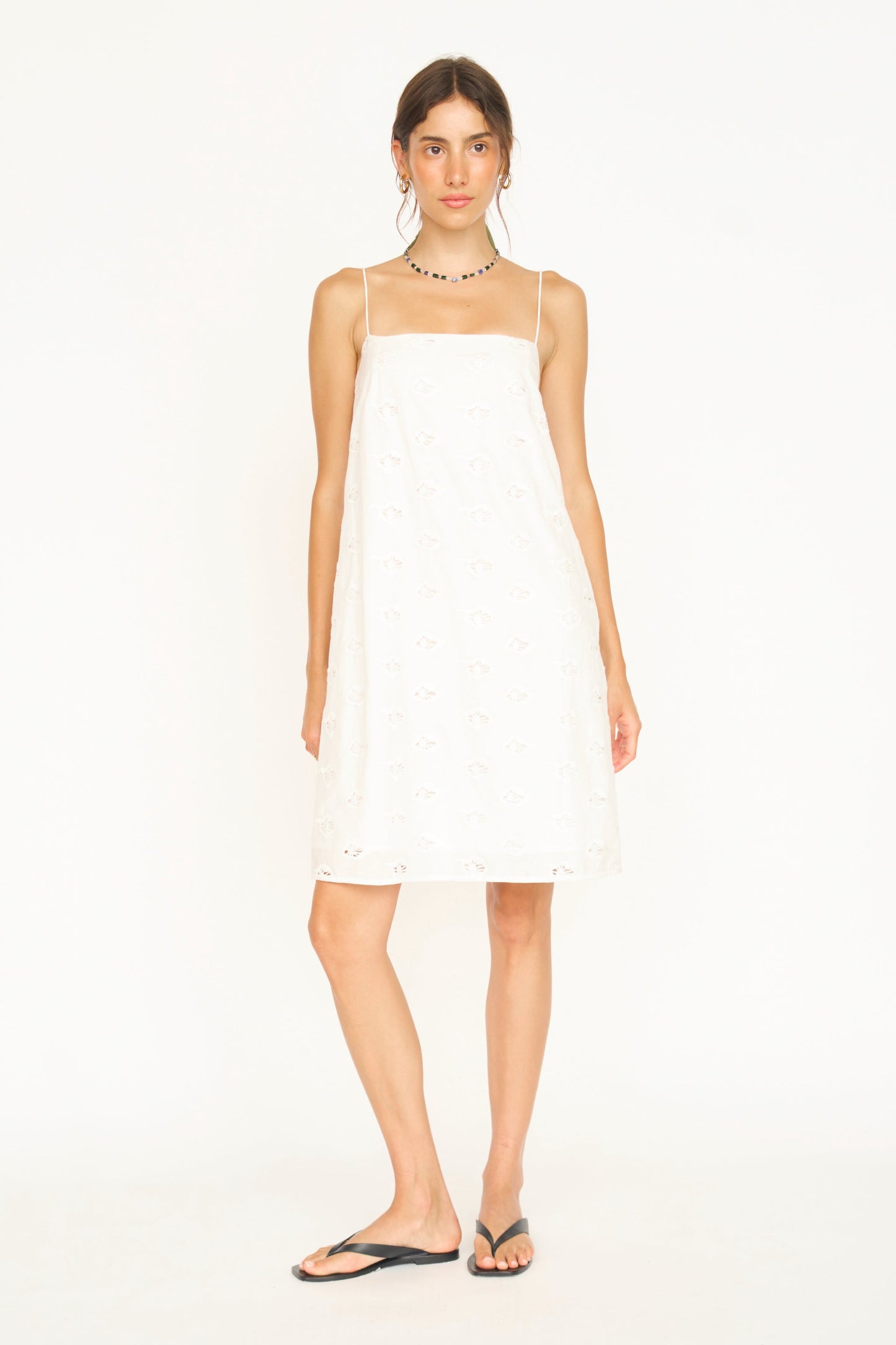 White eyelet mini dress on a hanger in store
