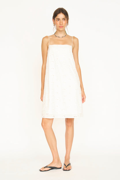 White eyelet mini dress on a hanger in store