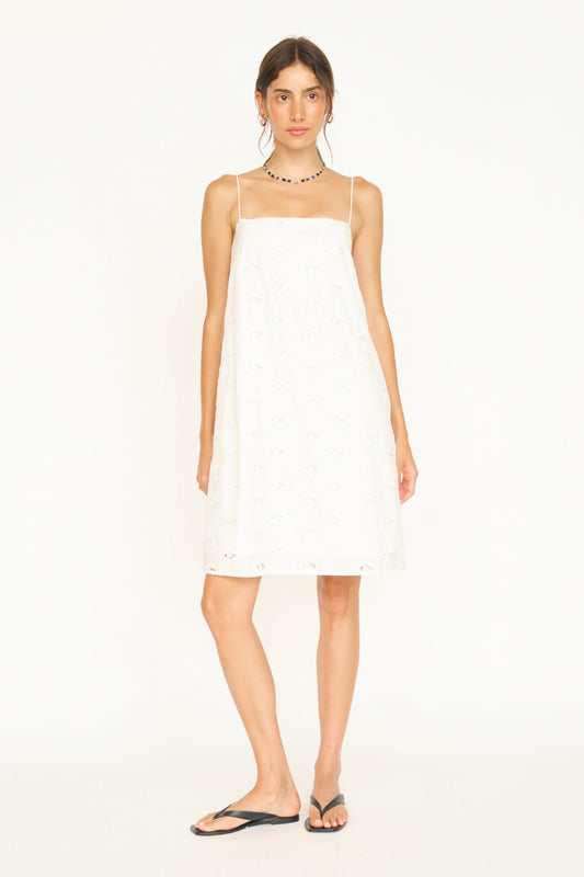 White eyelet mini dress on a hanger in store