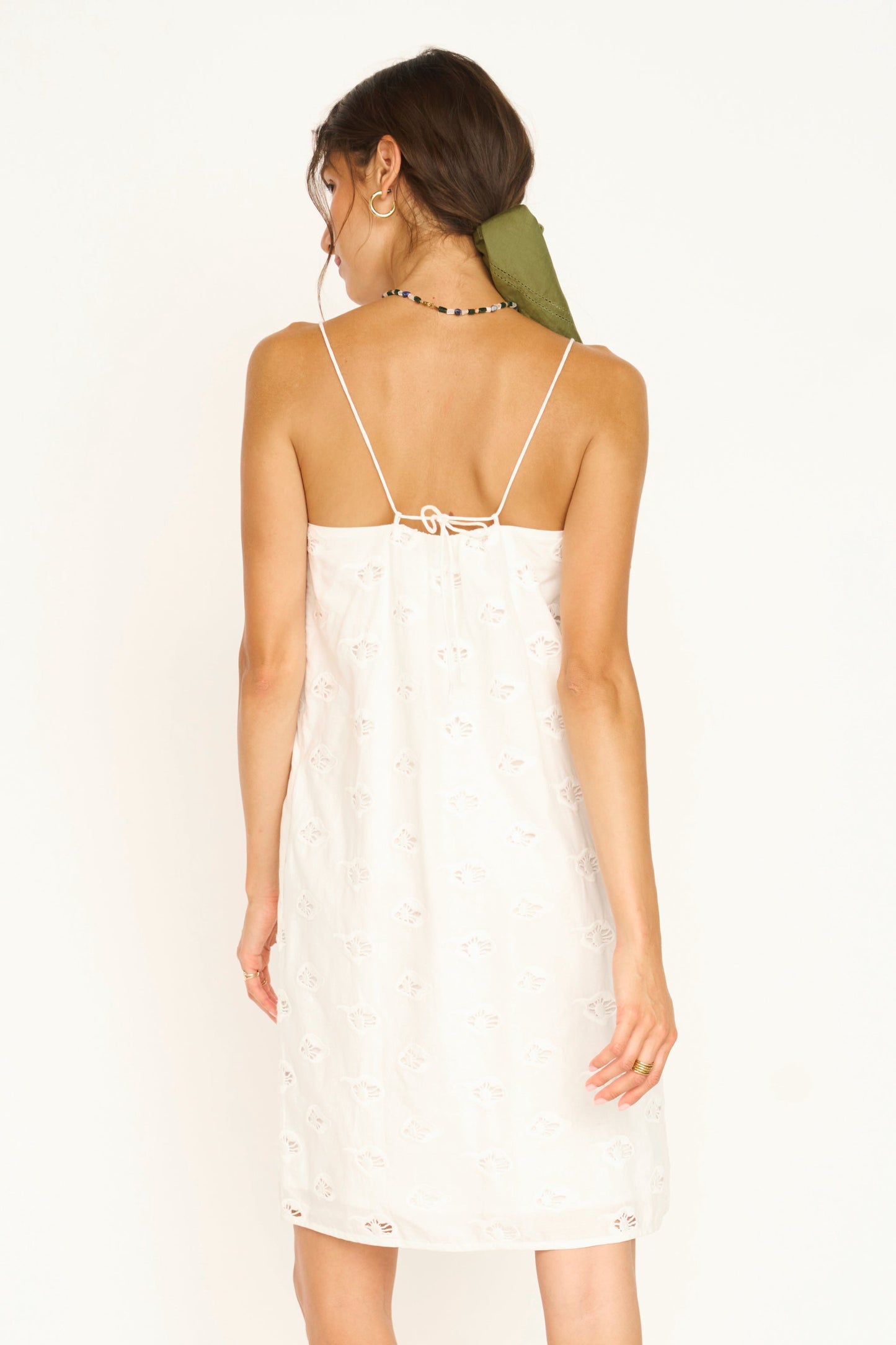 White eyelet mini dress on a hanger in store