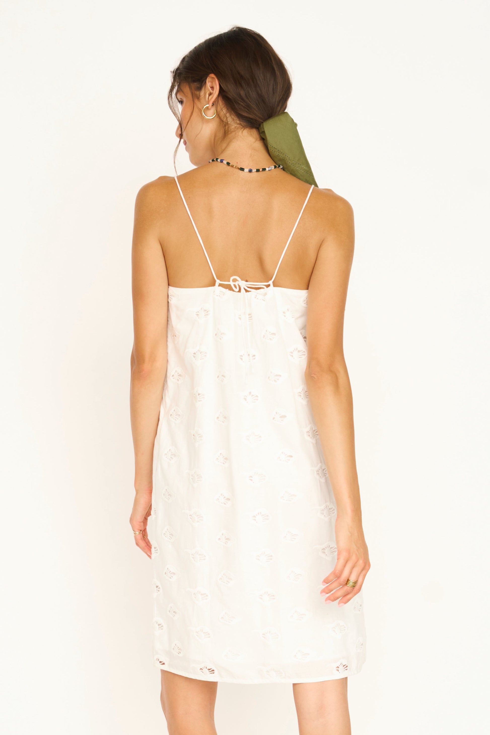 White eyelet mini dress on a hanger in store