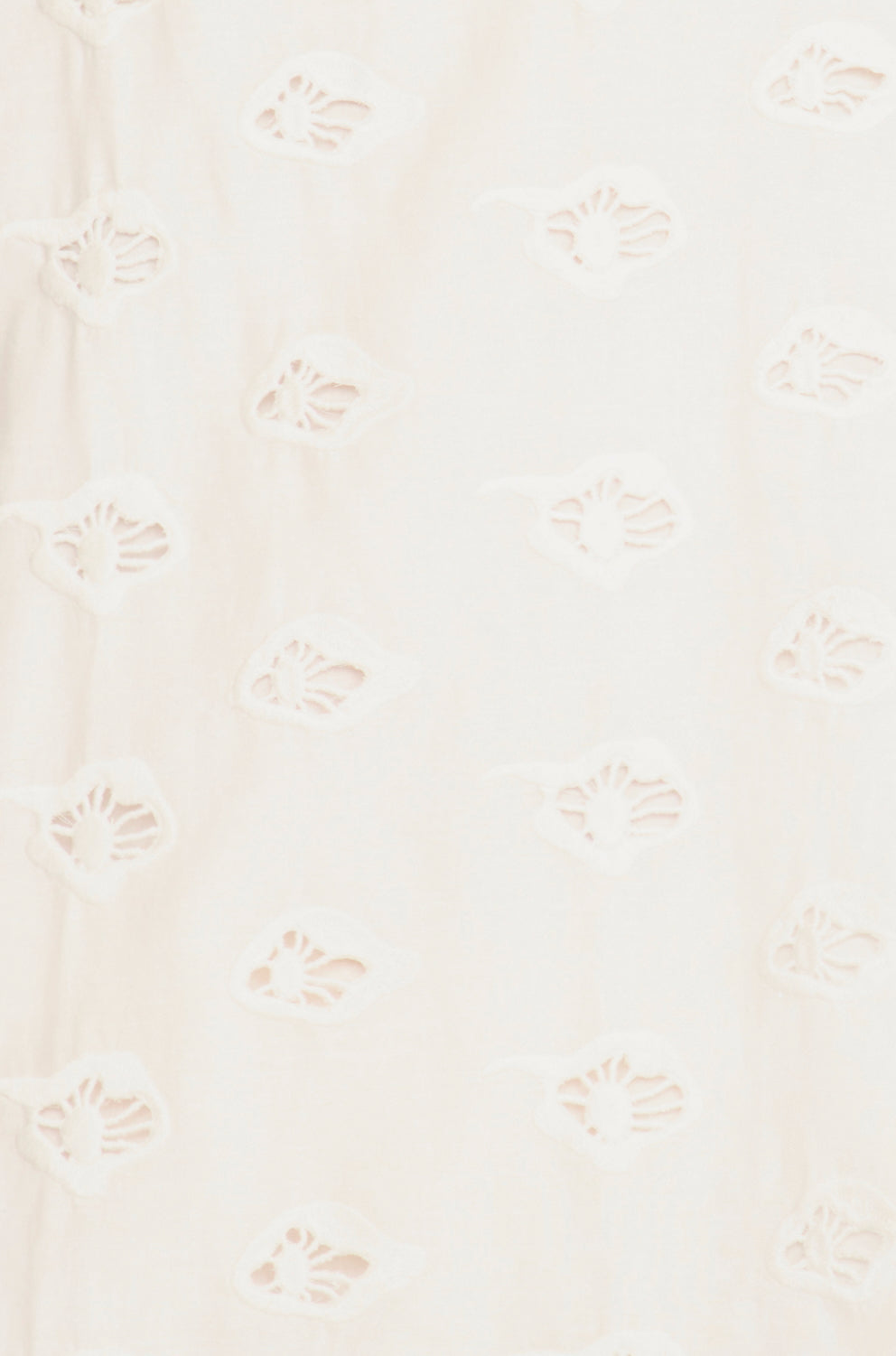 White eyelet mini dress on a hanger in store