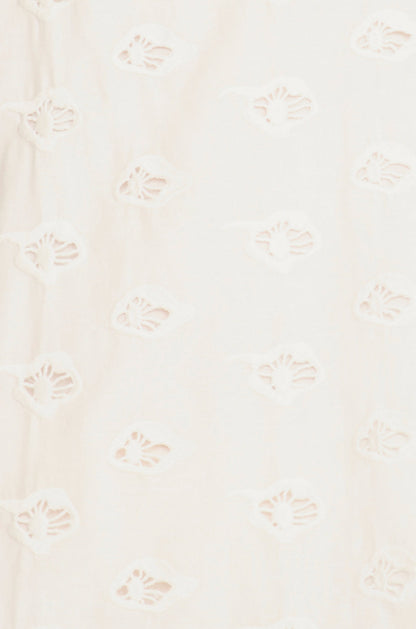 White eyelet mini dress on a hanger in store